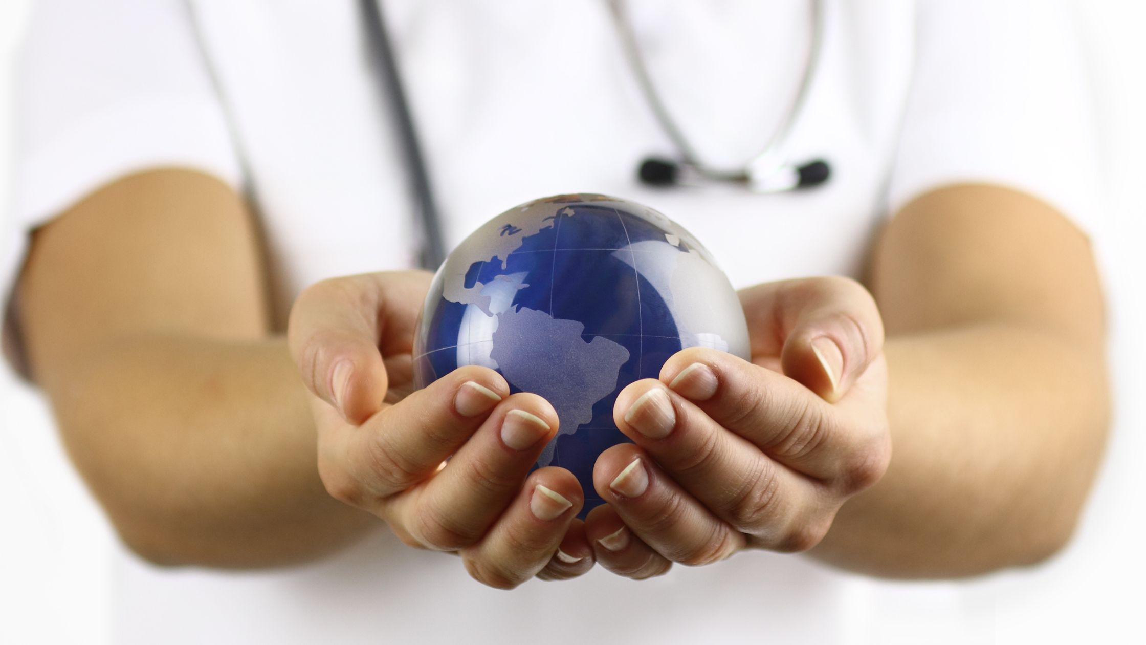 A healthcare worker holds a navy blue globe in her hands, representing international mental health.