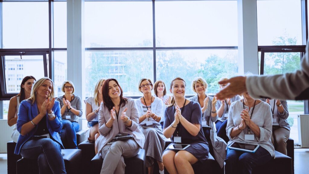 A group of corporate professionals are pictured clapping after completing a mental health training session.