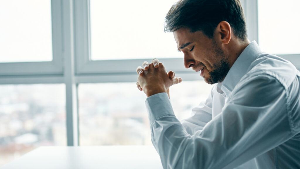 A man in a dress shirt cries in an office, representing the importance of supporting employees in crisis.